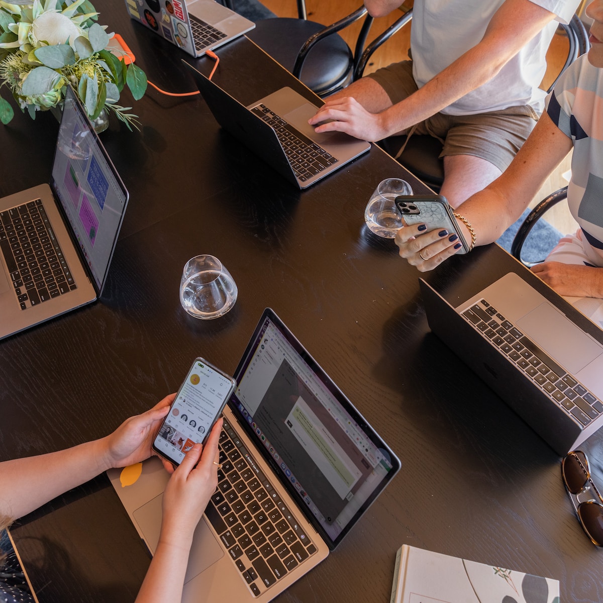 Photo by S O C I A L . C U T a group of people sitting around a table with laptops